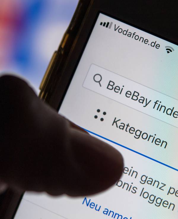 Eine Frau hält ein Smartphone mit der geöffneten eBay-App in der Hand.
