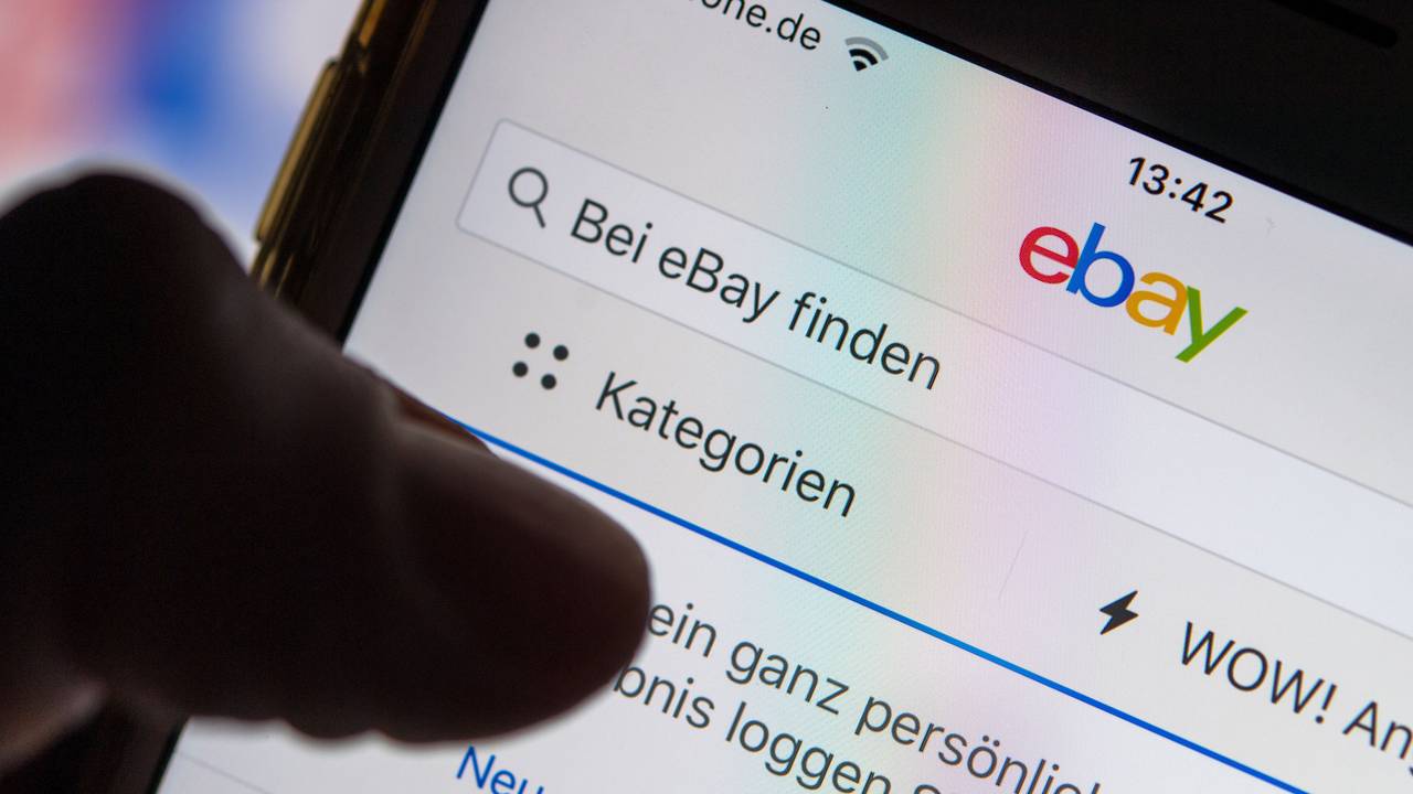 Eine Frau hält ein Smartphone mit der geöffneten eBay-App in der Hand.