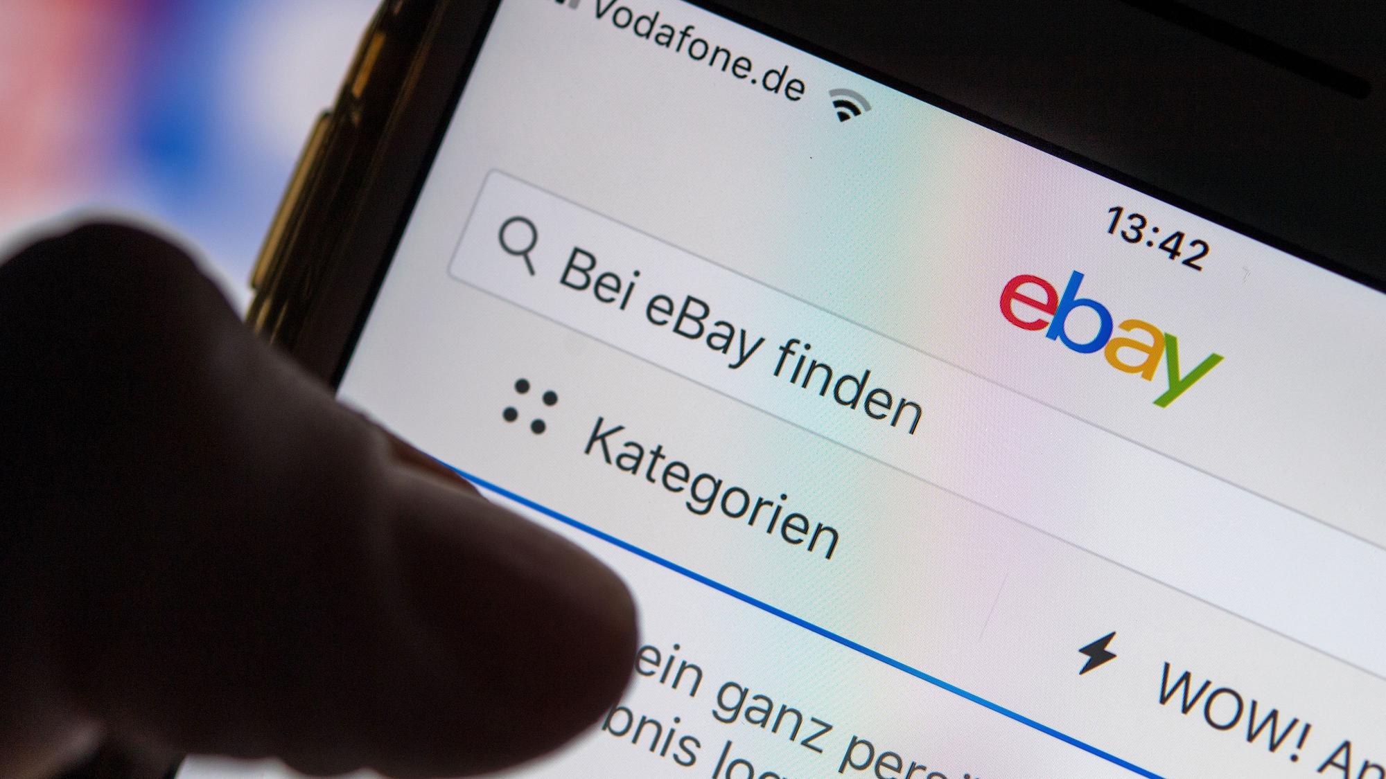 Eine Frau hält ein Smartphone mit der geöffneten eBay-App in der Hand.
