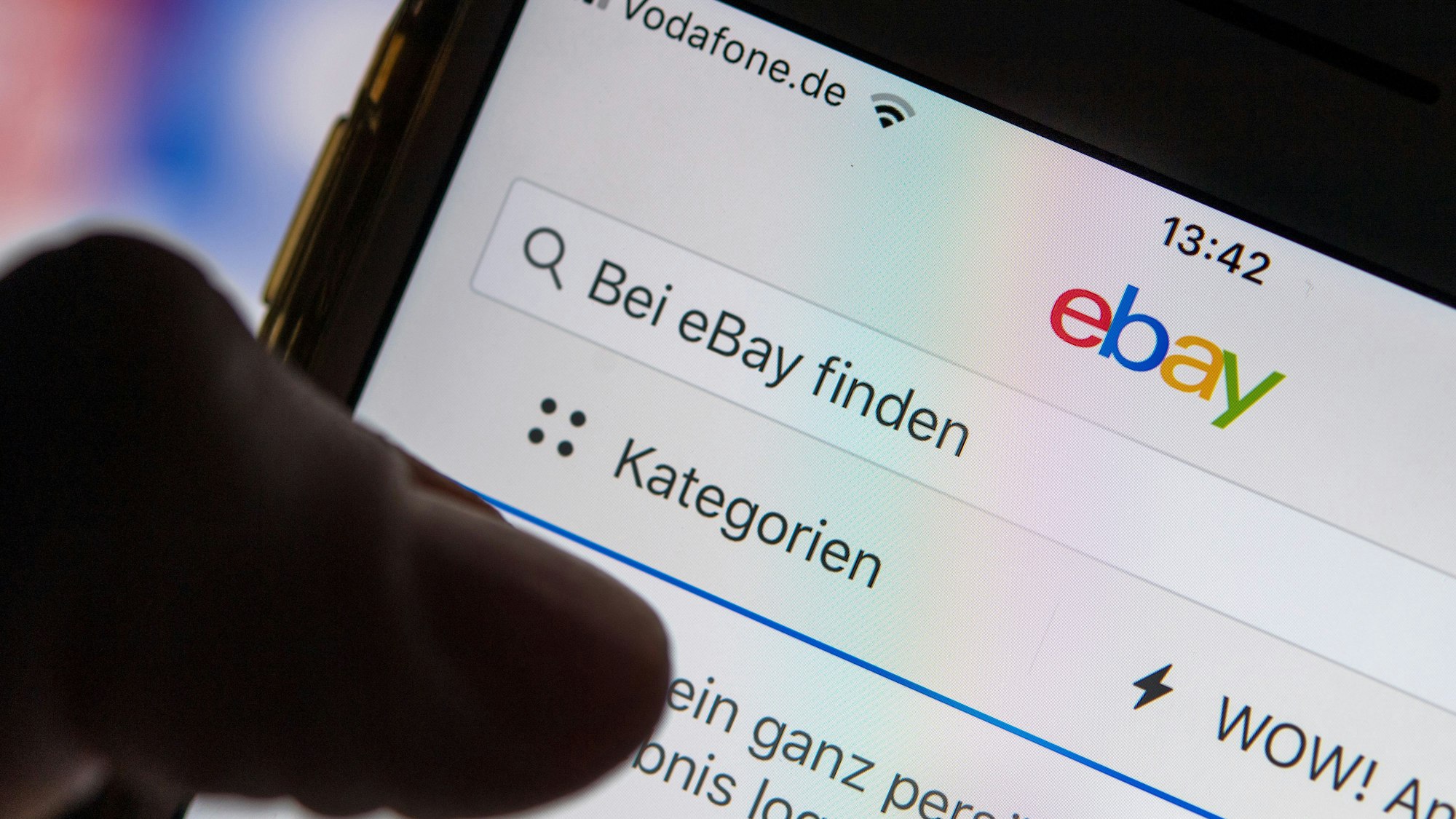 Eine Frau hält ein Smartphone mit der geöffneten eBay-App in der Hand.