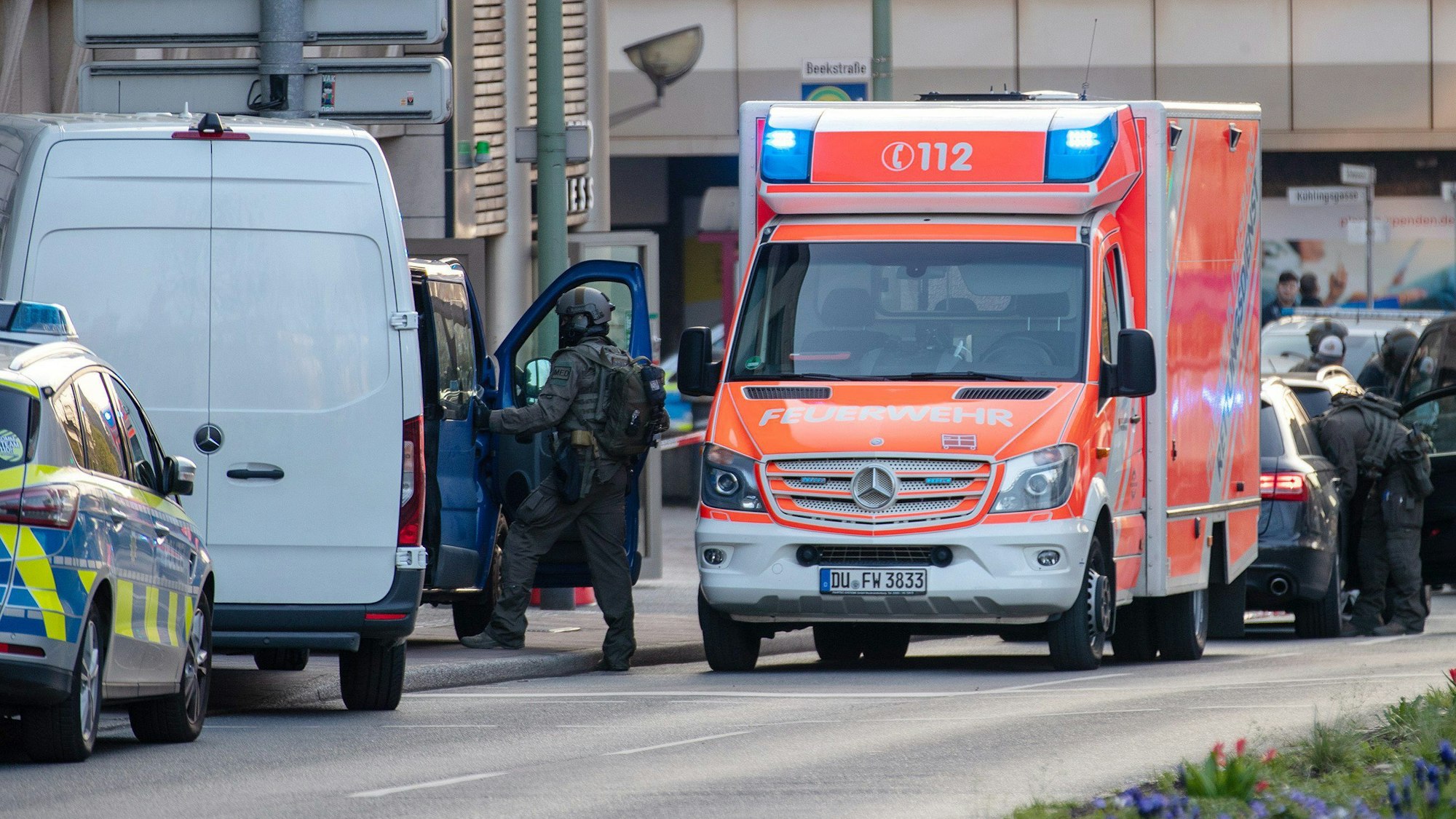 Polizisten steigen bei einem Einsatz aus ihren Autos. Auch ein Streifen- und ein Rettungswagen stehen auf der Straße.