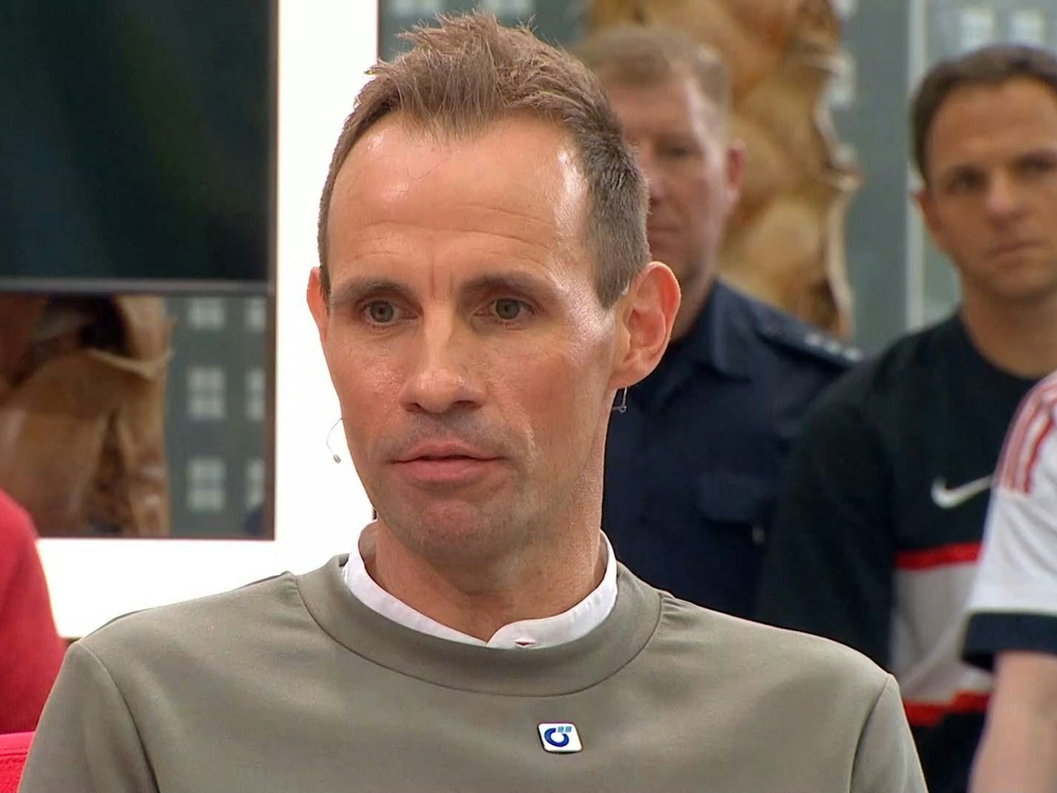 Sascha Stegemann sitzt als Gast beim Doppelpass. Im Hintergrund ist ein uniformierter Polizist zu sehen.