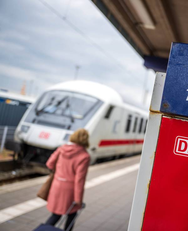 Touristen laufen mit Rollkoffern am Bahnhof Norddeich-Mole entlang.