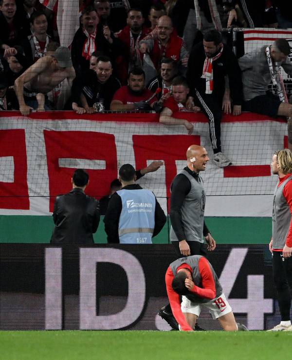 Leipzigs Andre Silva geht vor dem Freiburger Fanblock zu Boden.
