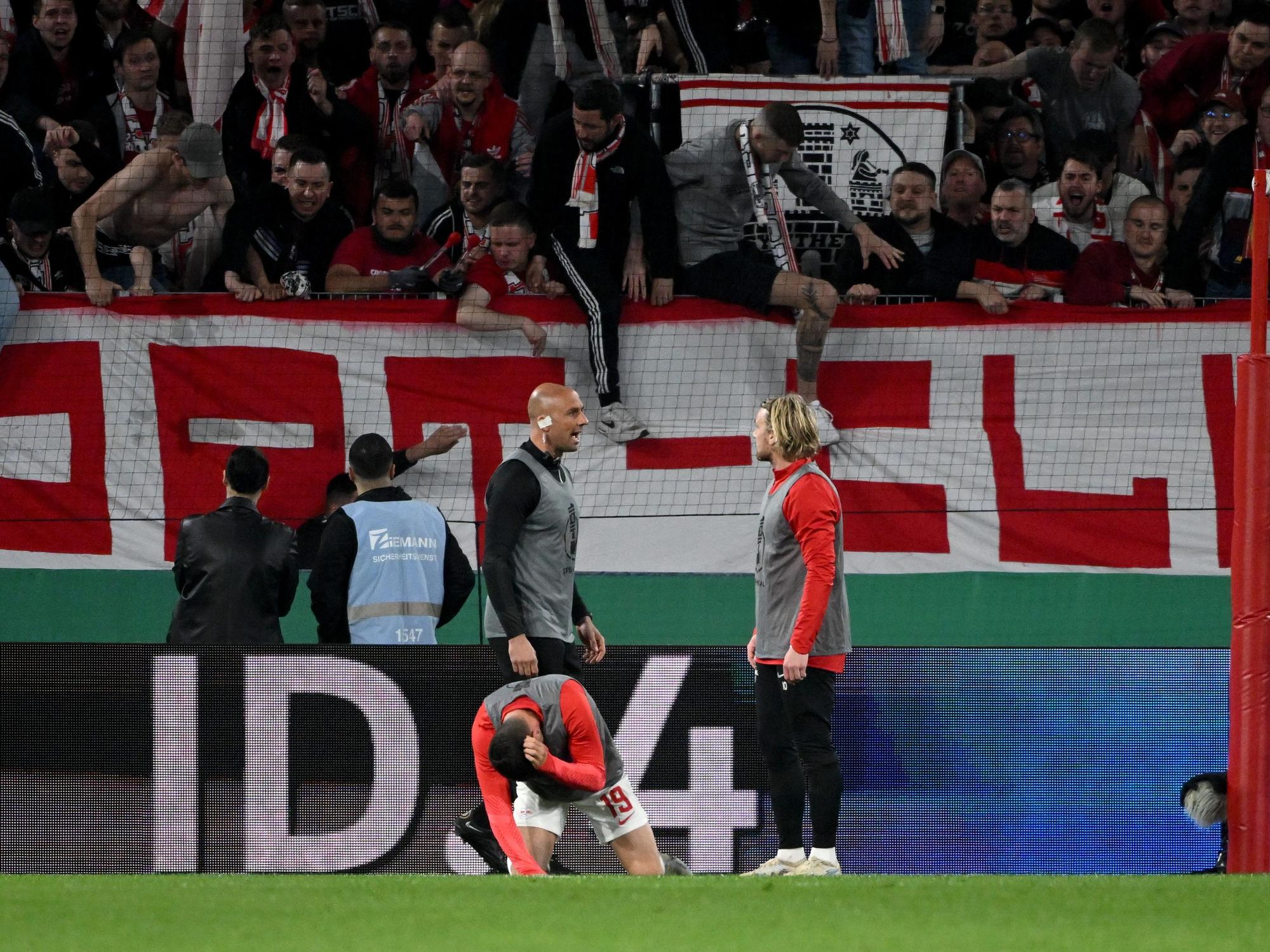 Leipzigs Andre Silva geht vor dem Freiburger Fanblock zu Boden.