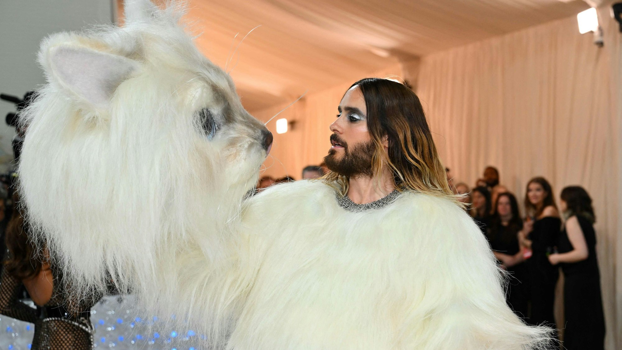 Jared Leto hat den Kopf seines Kostüms abgezogen und hält ihn neben seinen.