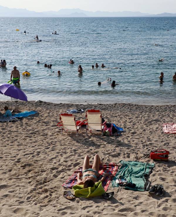 Das undatierte Symbolfoto zeigt mehrere Menschen, die am Strand liegen oder im Meer schwimmen.