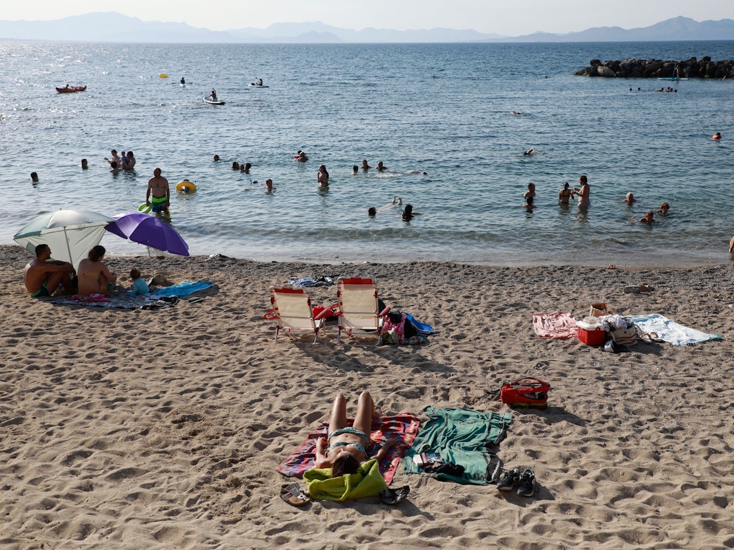 Das undatierte Symbolfoto zeigt mehrere Menschen, die am Strand liegen oder im Meer schwimmen.