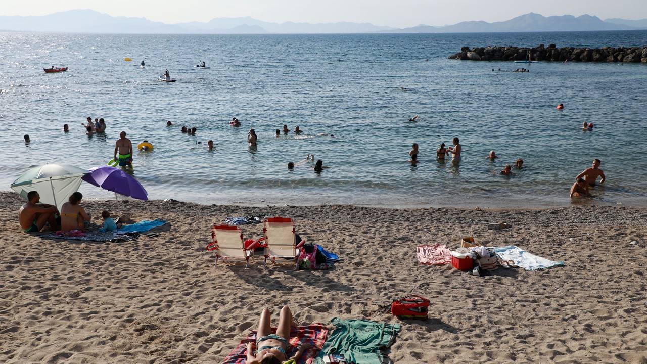 Das undatierte Symbolfoto zeigt mehrere Menschen, die am Strand liegen oder im Meer schwimmen.