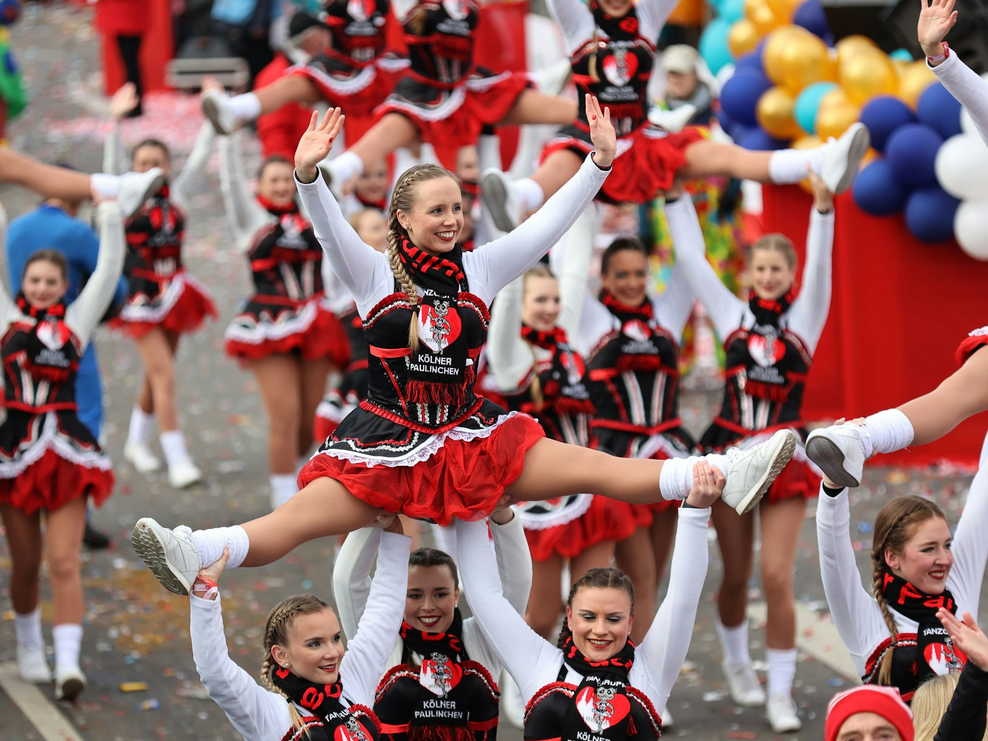 Die Kölner Paulinchen tanzen beim Rosenmontagszug in Köln auf der Straße.