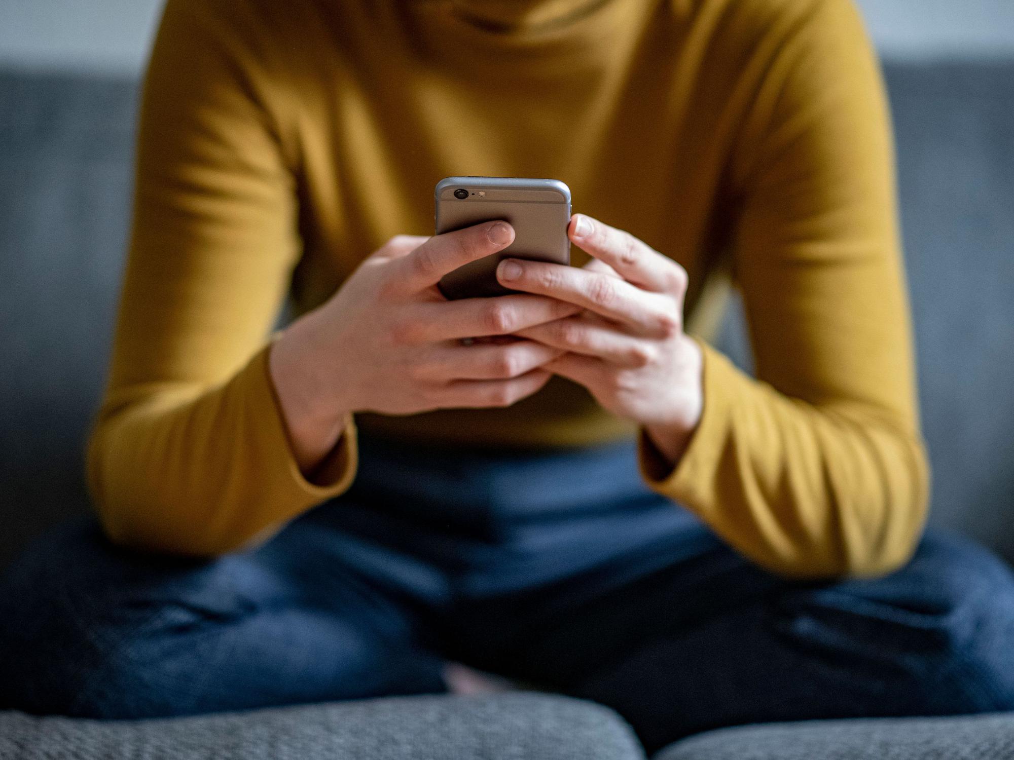 Eine junge Frau hält ein Smartphone in der Hand, hier im April 2021 in Berlin.