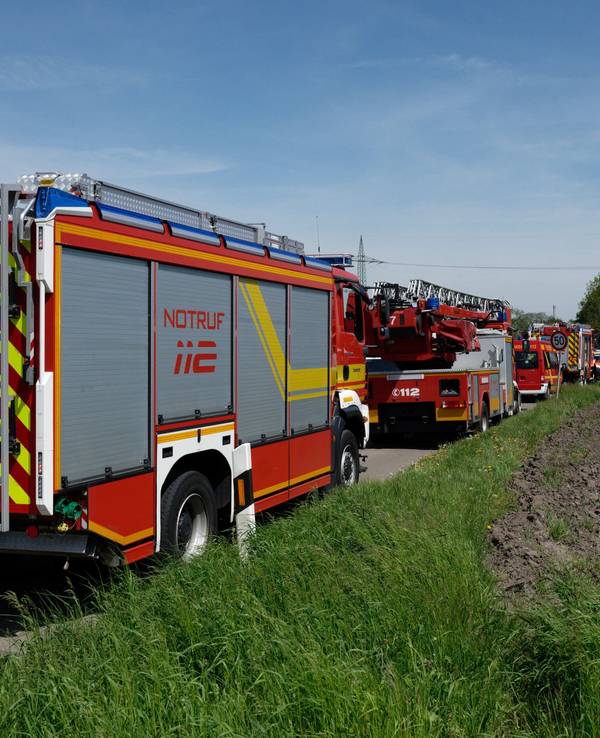 Fahrzeuge der Einsatzkräfte stehen am 4. Mai 2023 auf einer zum Unfallort führenden Straße. Bei dem Unfall in Hürth bei Köln sind am Donnerstag nach Angaben der Bundespolizei zwei Menschen ums Leben gekommen.
