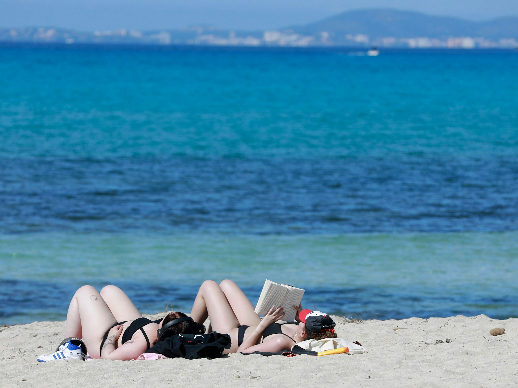 Zwei junge Frauen genießen am 9. April 2023 die Sonne an der Playa de Palma auf Mallorca und sonnen sich.