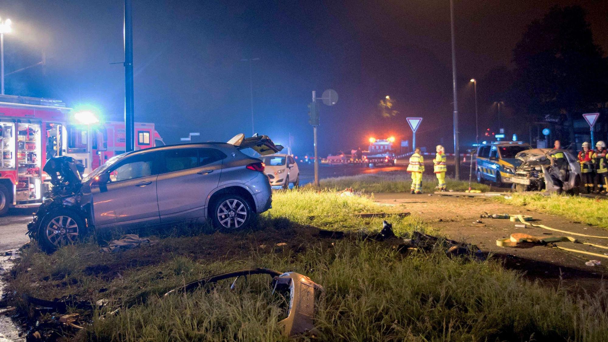 Einsatzkräfte von Feuerwehr und Polizei sind an einer Unfallstelle im Einsatz, wo zwei schwer beschädigte Autos stehen.