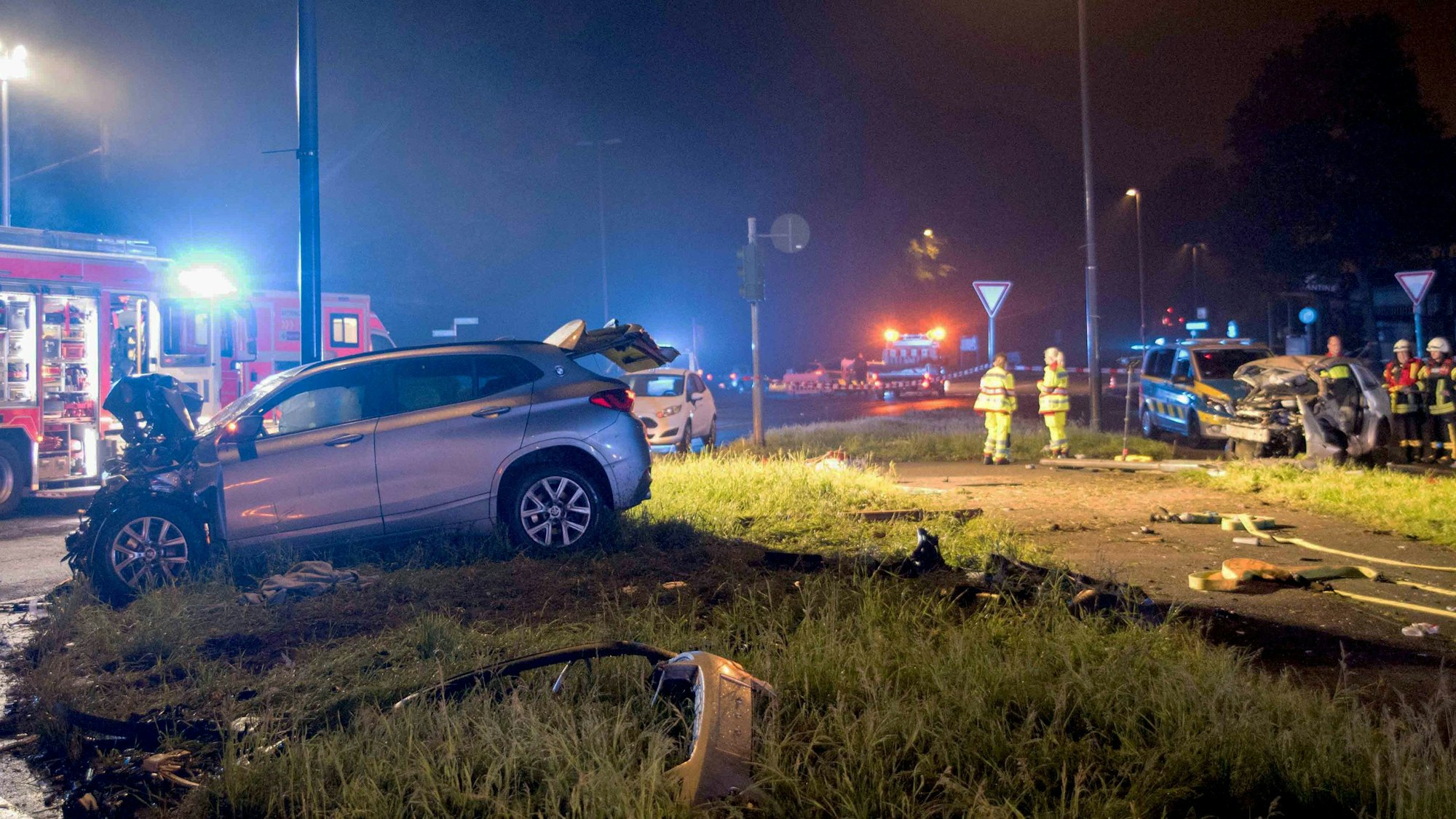 Einsatzkräfte von Feuerwehr und Polizei sind an einer Unfallstelle im Einsatz, wo zwei schwer beschädigte Autos stehen.