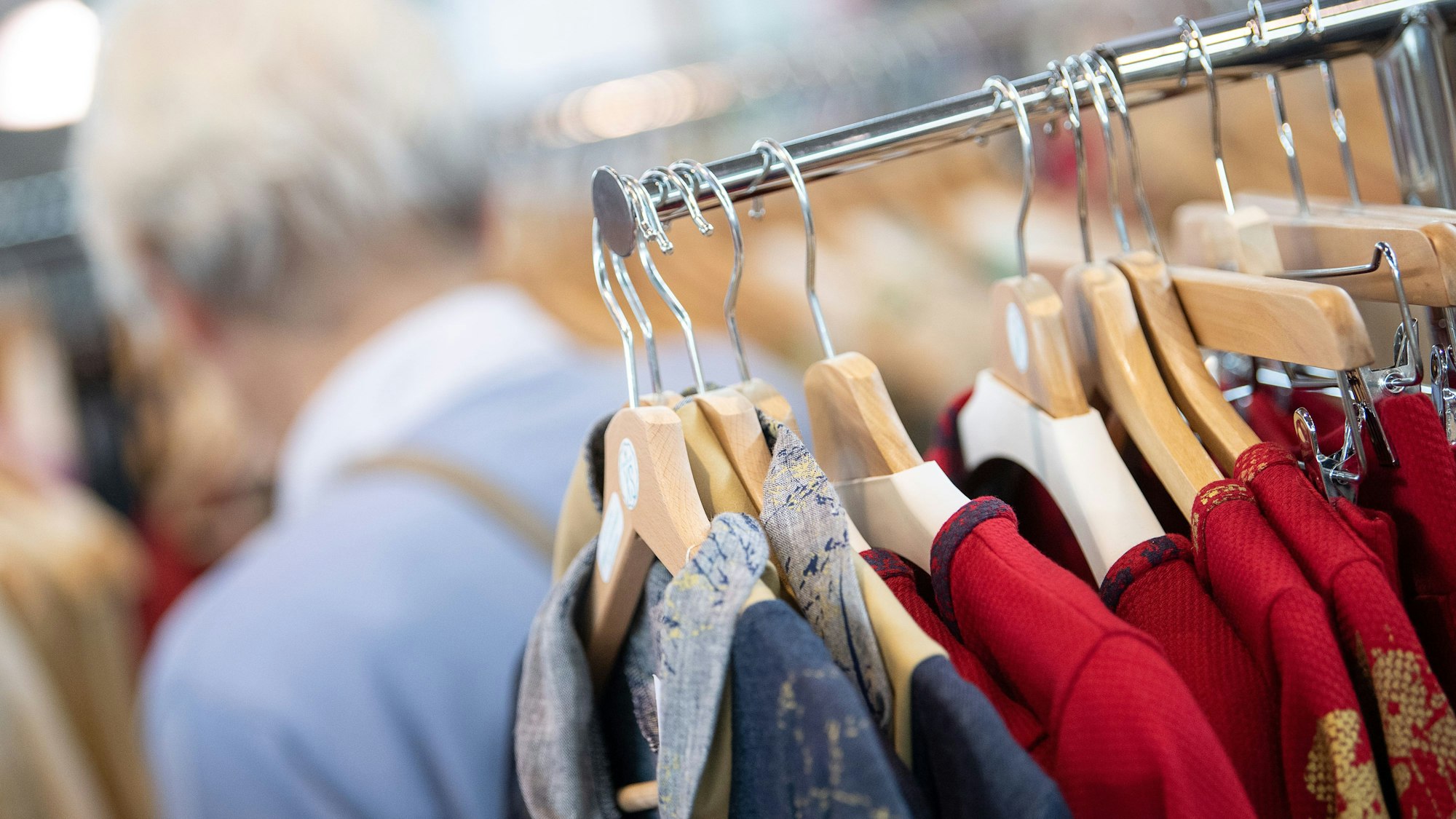 Kleidung hängt an Kleiderbügeln an einer Stange.
