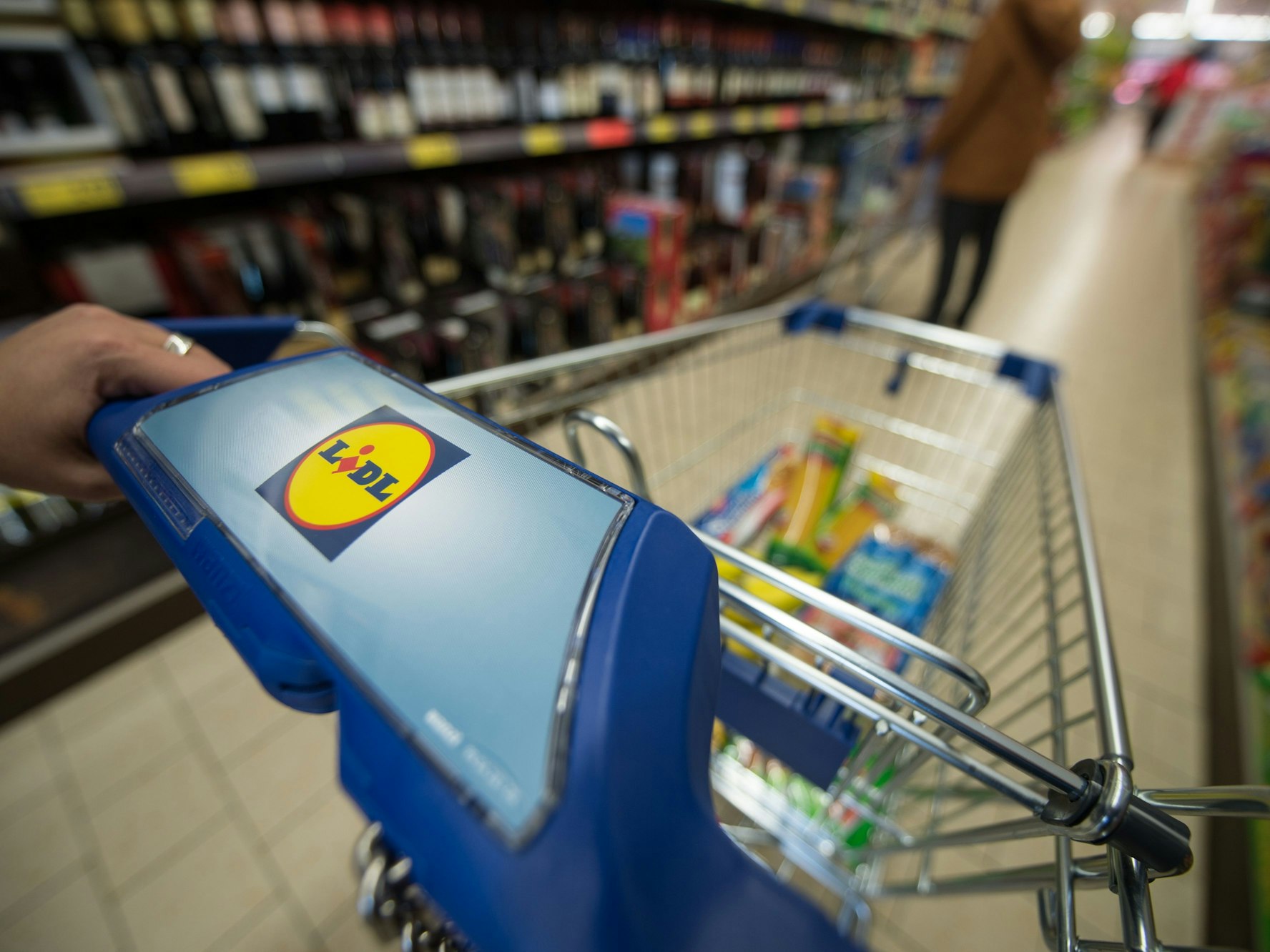 Eine Frau schiebt in einer Filiale des Lebensmitteldiscounters Lidl einen Einkaufswagen durch die Regalreihen. (März 2015, Stuttgart)