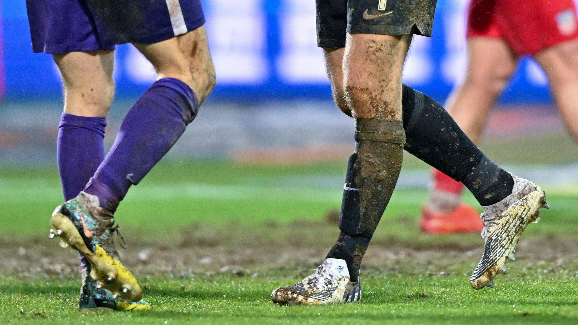 Fußballspieler stehen sich auf matschigem Boden gegenüber.