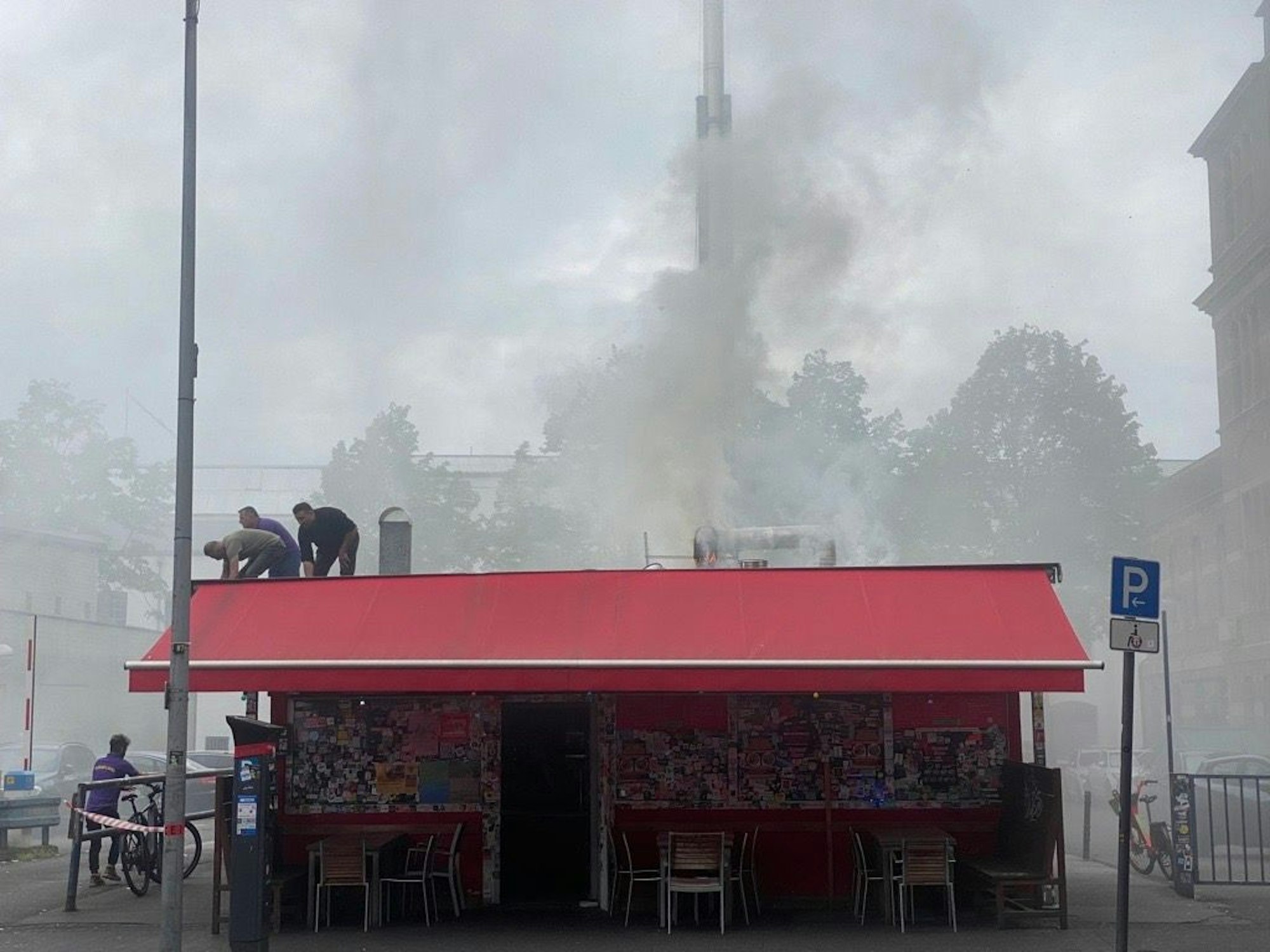 Feuerwehrleute und eine Polizistin stehen auf dem Dach des Kebapland.