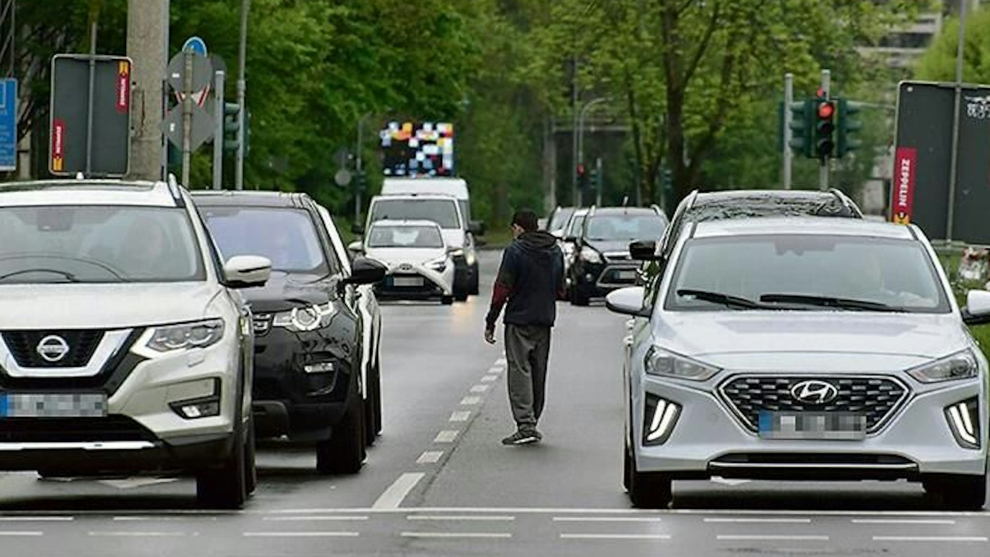 Ganz in Schwarz gekleidet läuft dieser Obdachlose zwischen den Autos entlang.