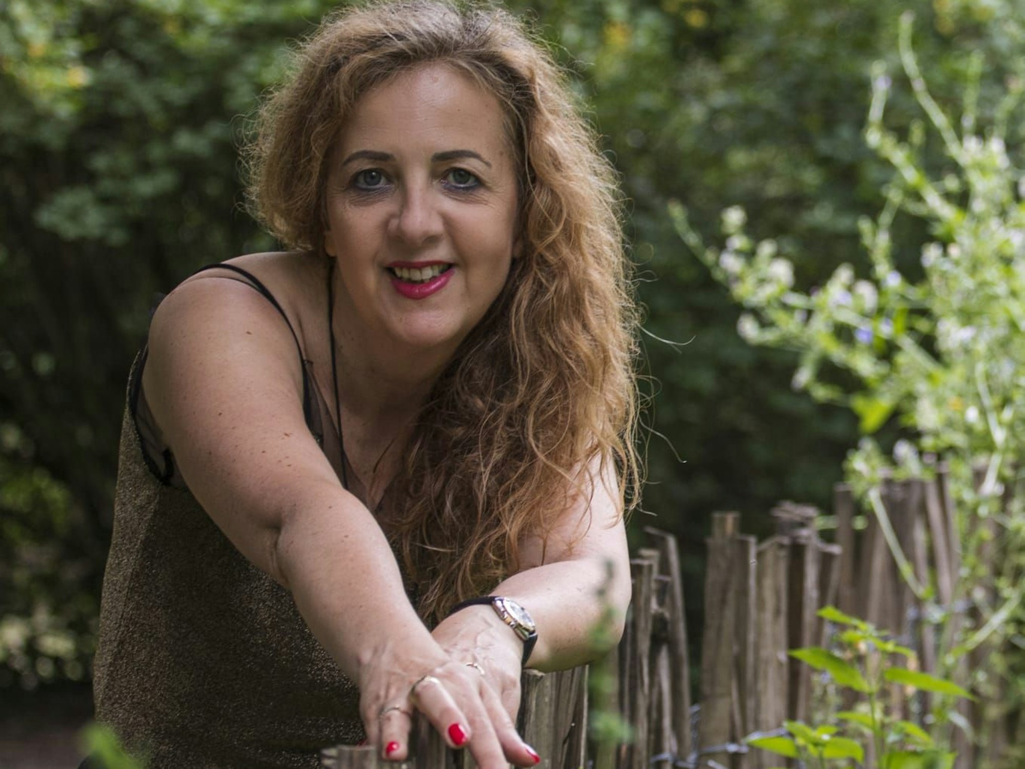 Autorin Renate Kaiser lehnt an einem Zaun und schaut in die Kamera.