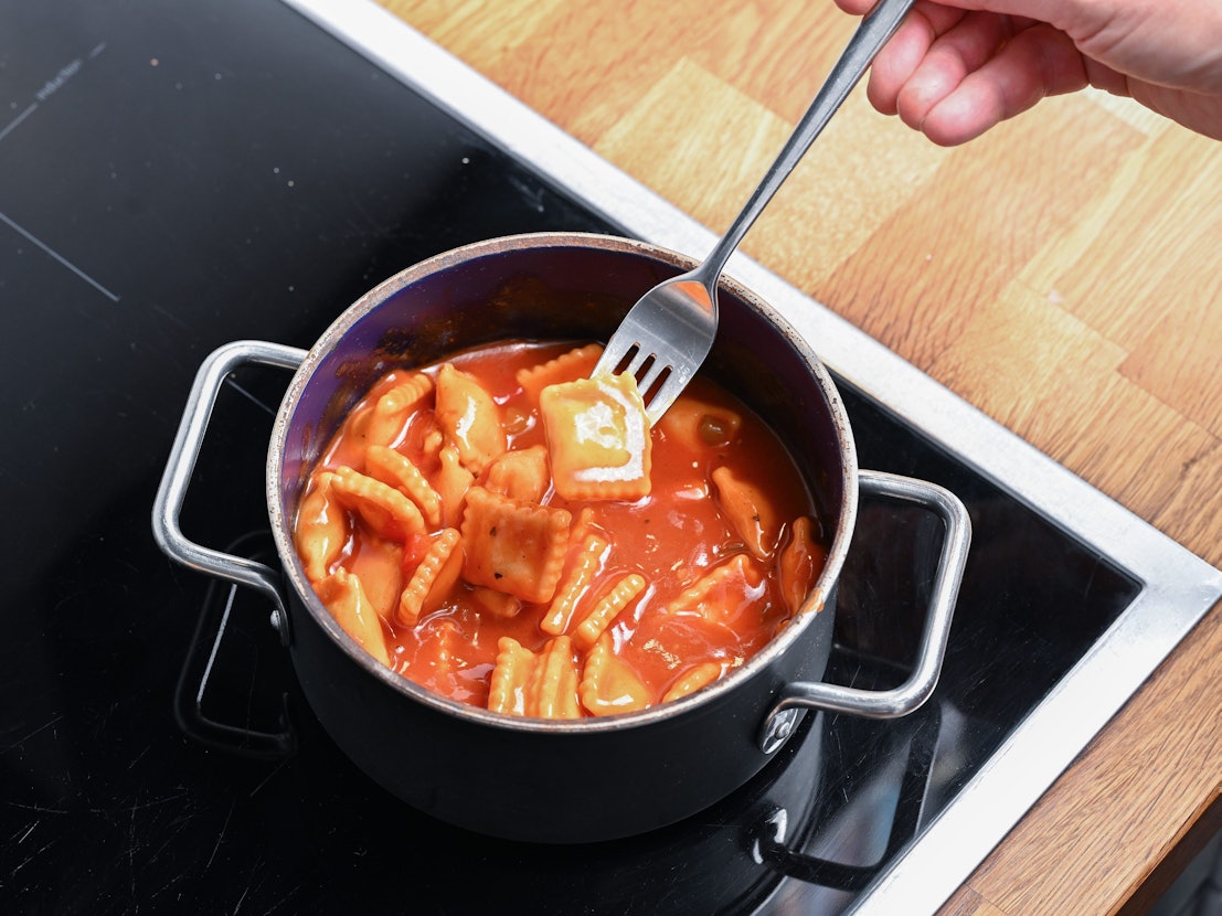 Ein Topf mit Ravioli aus der Dose steht auf einem Herd.