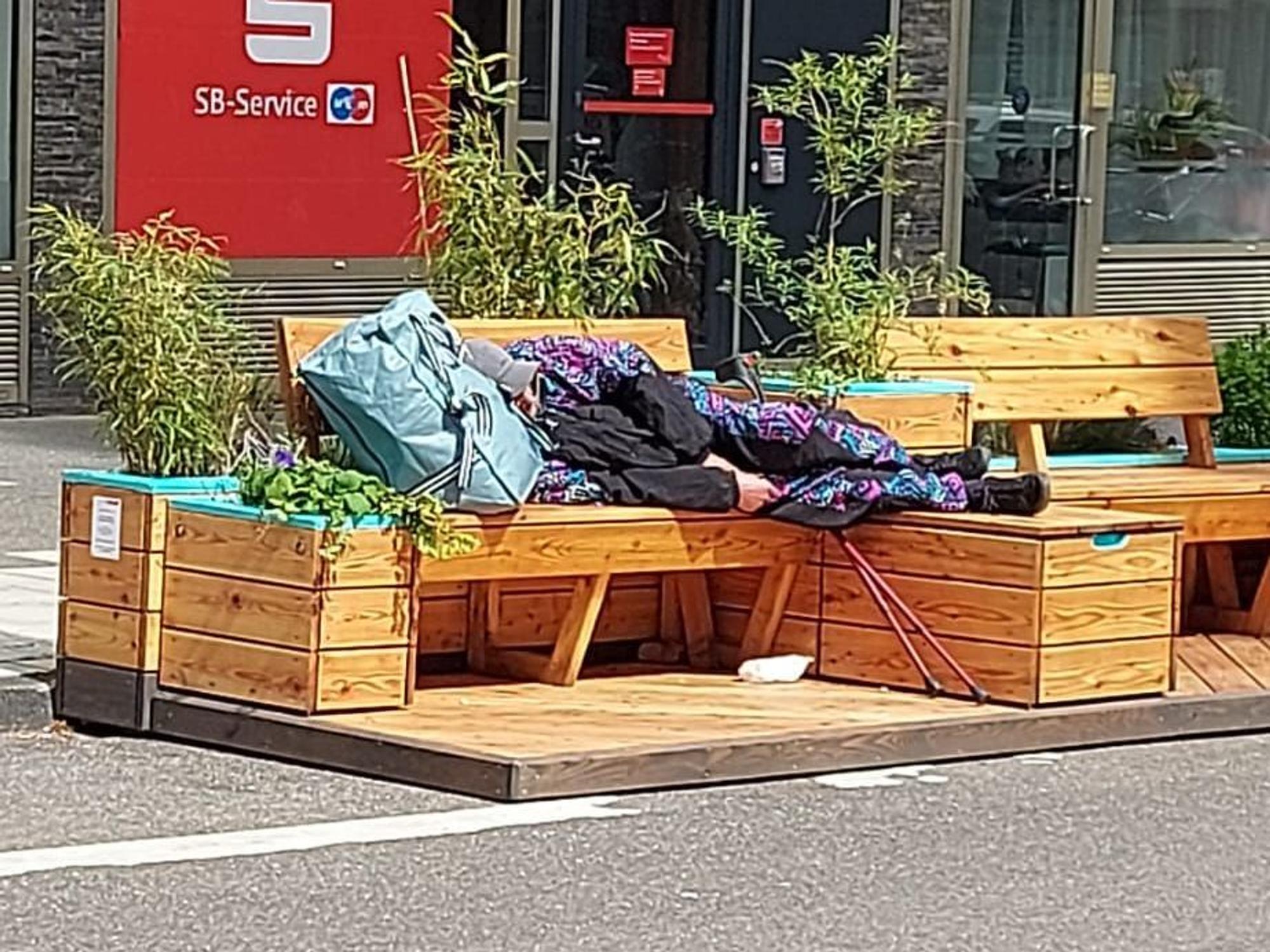 Ein Obdachloser liegt auf einer Bank auf der Deutzer Freiheit.