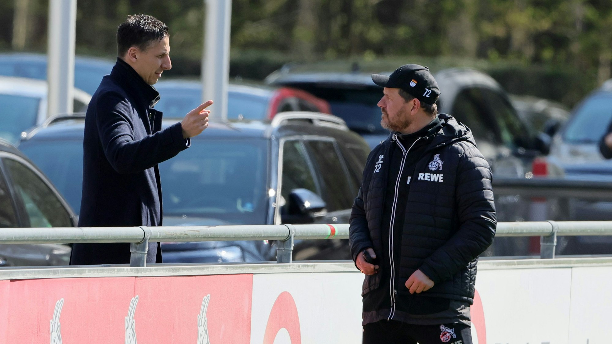 Christian Keller und Steffen Baumgart unterhalten sich beim Training des 1. FC Köln an der Bande.