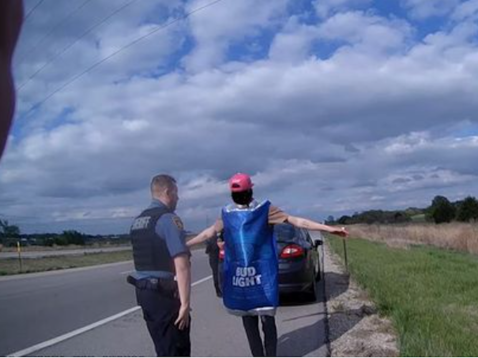 Ein amerikanischer Polizist überprüft Verdächtigen in Bud Light Bier-Kostüm.