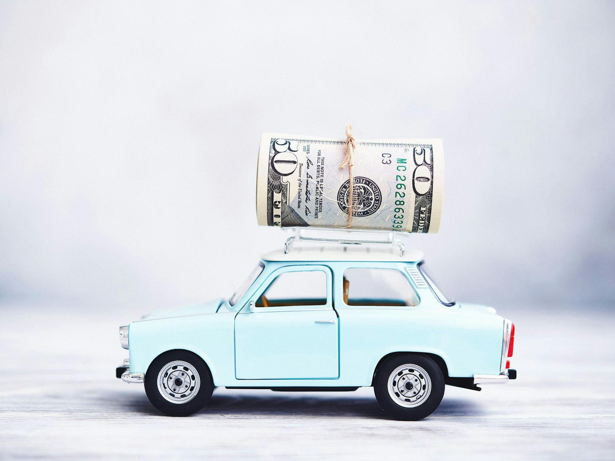 Ein blaues Auto mit Geldscheinen auf dem Dach.