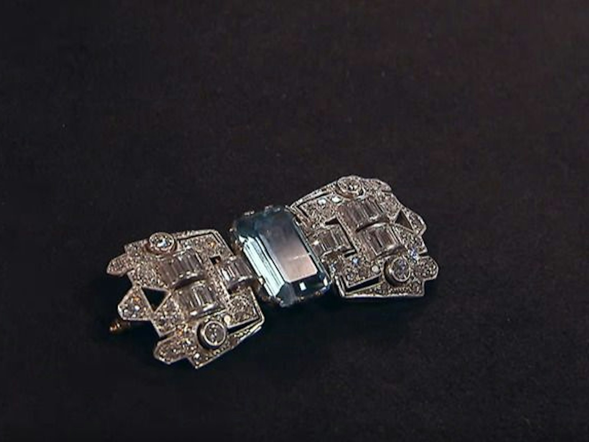 Diamantbestückte Brosche in Form einer Schnalle. In der Mitte des Schmuckstückes ist ein blauer Aquamarin-Stein.