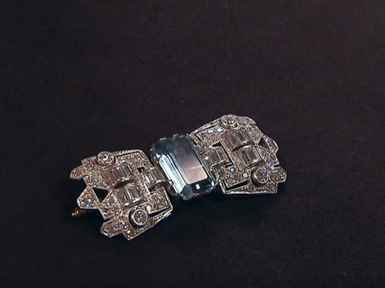 Diamantbestückte Brosche in Form einer Schnalle. In der Mitte des Schmuckstückes ist ein blauer Aquamarin-Stein.