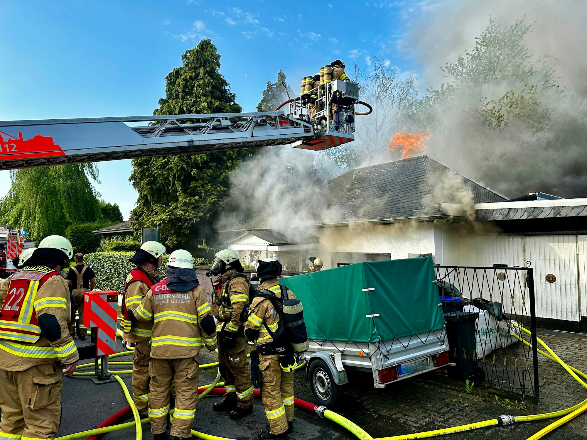 Das Feuer im Stadtteil Bärbroich von Bergisch Gladbach; Feuerwehr im Einsatz bei einem Brand in Bergisch Gladbach. Hohe Rauchwolken steigen aus dem Haus.