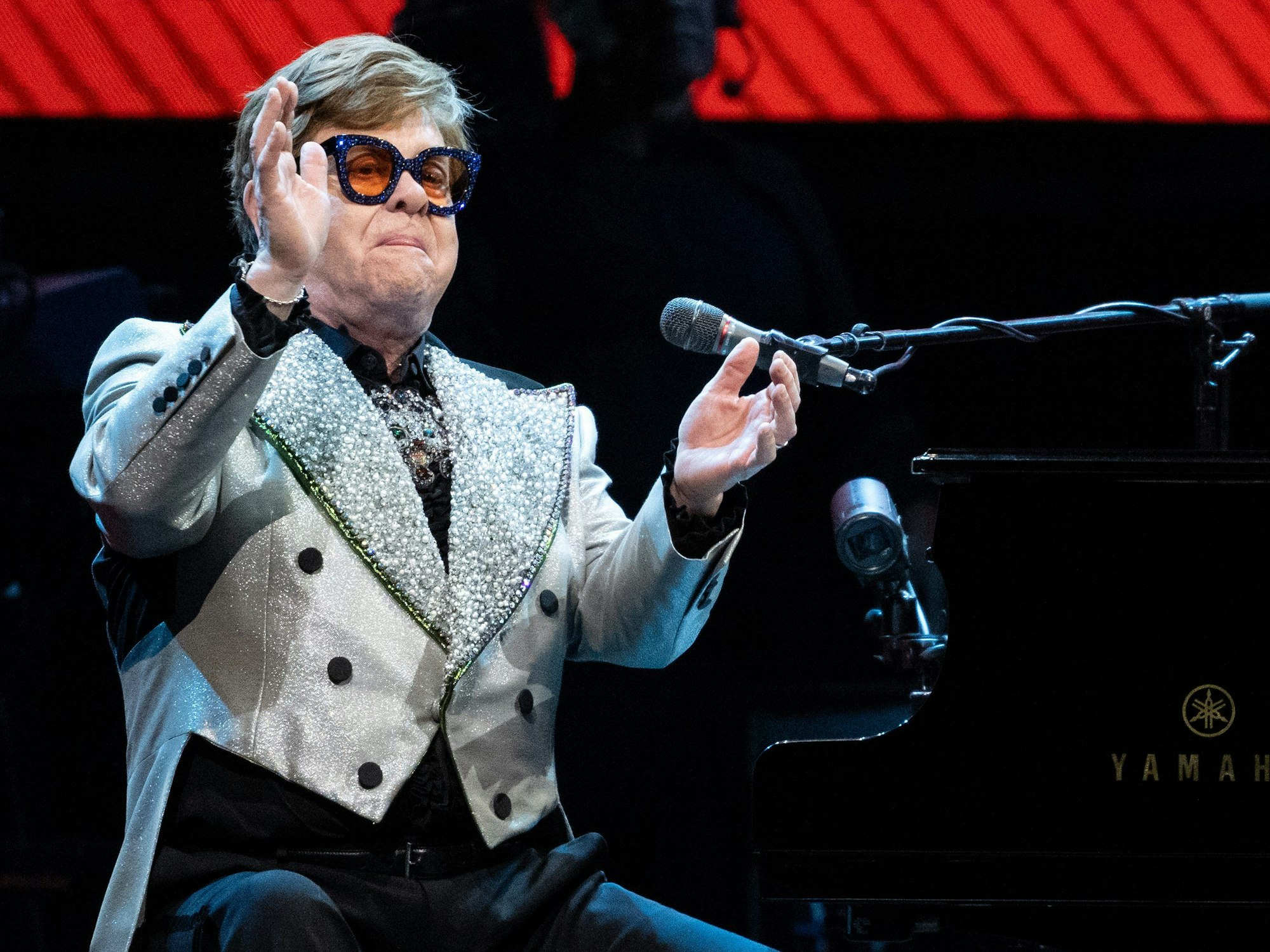 Der Sänger und Pianist Elton John sitzt in der Olympiahalle bei einem Konzert im Rahmen seiner „Farewell Yellow Brick Road Tour 2023“ auf der Bühne.
