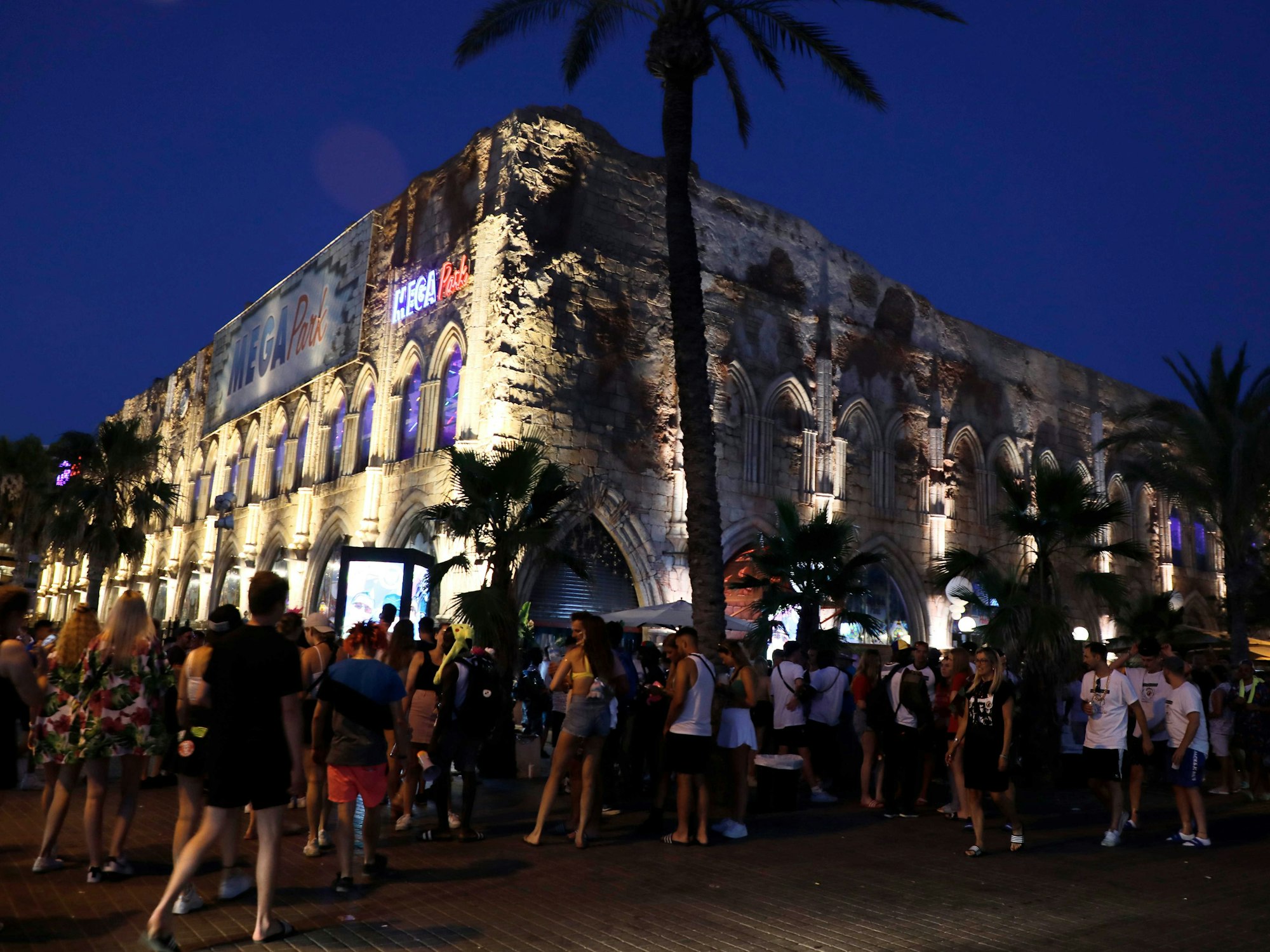 Menschen gehen neben dem Megapark am Strand von Arenal auf Mallorca vorbei.