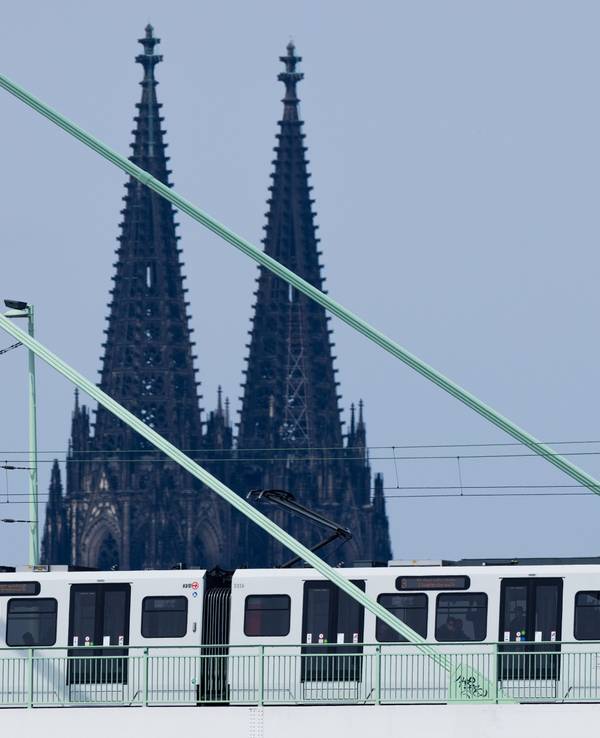 Eine Straßenbahn der Kölner Verkehrsbetriebe fährt über die Severinsbrücke vor der Kulisse des Kölner Doms.