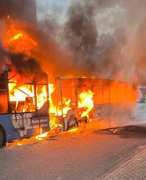 Einsatzkräfte der Feuerwehr löschen am Samstag, 13. Mai 2023, zwei brennende Reisebusse bei einer Lagerhalle in Alsdorf-Schaufenberg nahe Aachen.