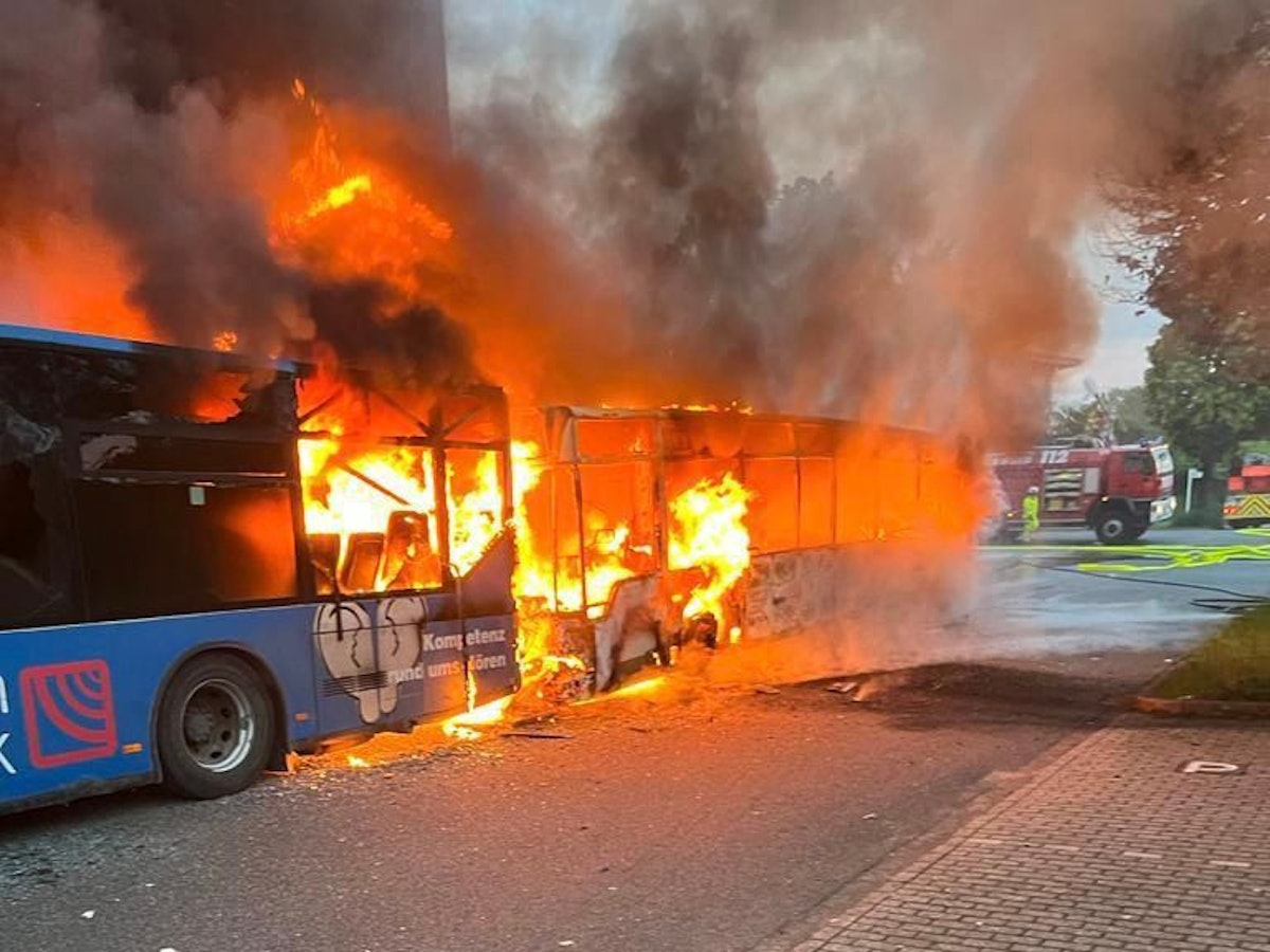Einsatzkräfte der Feuerwehr löschen am Samstag, 13. Mai 2023, zwei brennende Reisebusse bei einer Lagerhalle in Alsdorf-Schaufenberg nahe Aachen.