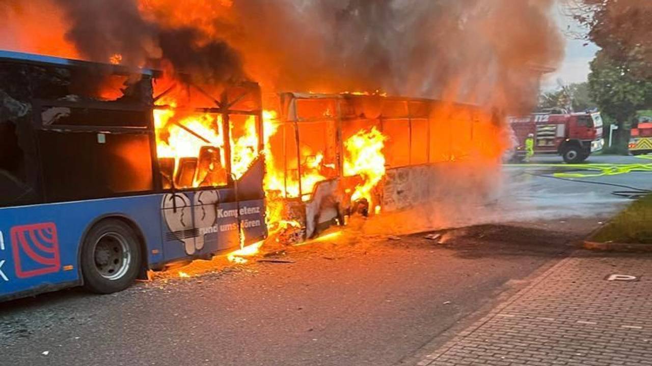 Einsatzkräfte der Feuerwehr löschen am Samstag, 13. Mai 2023, zwei brennende Reisebusse bei einer Lagerhalle in Alsdorf-Schaufenberg nahe Aachen.
