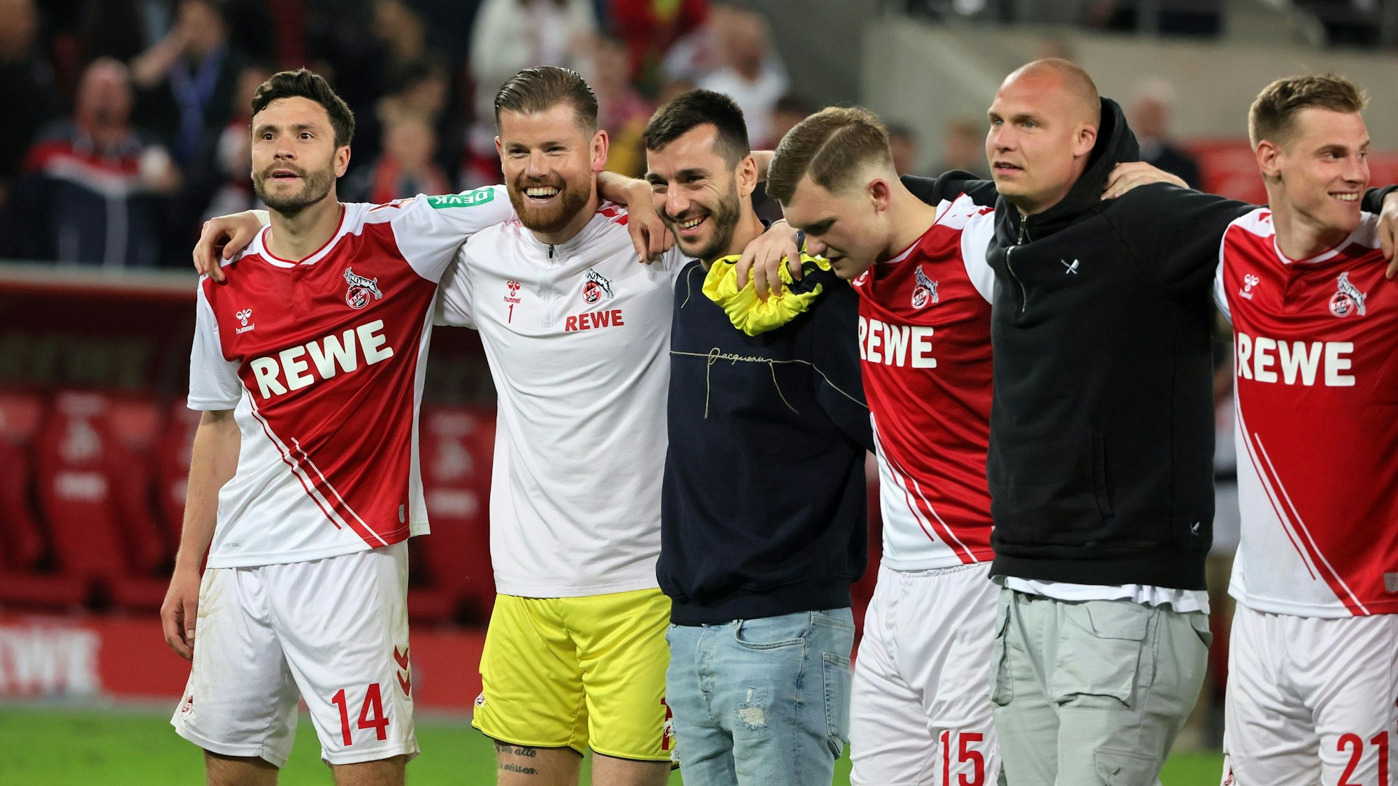 Die Profis des 1. FC Köln stehen Arm in Arm vor der Südkurve.
