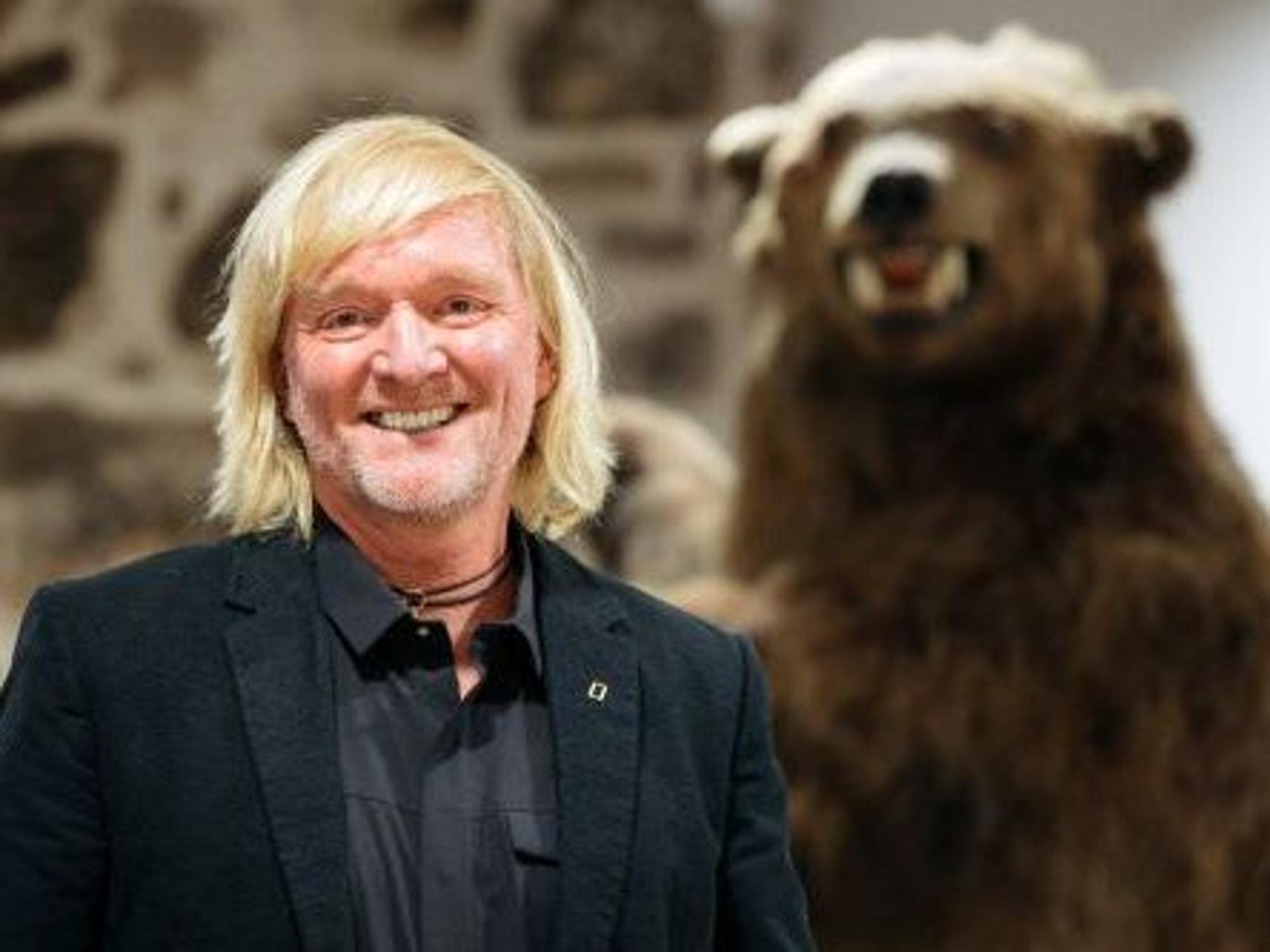 Andreas Kieling mit ausgestopften Braunbären im Hintergrund.