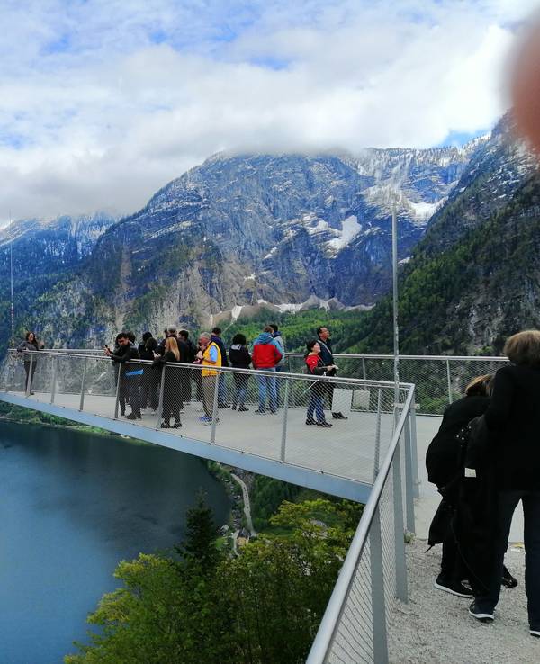 Touristen und Touristinnen stehen am 16. Mai 2023 auf einer Aussichtsplattform über dem Hallstätter See in Österreich.