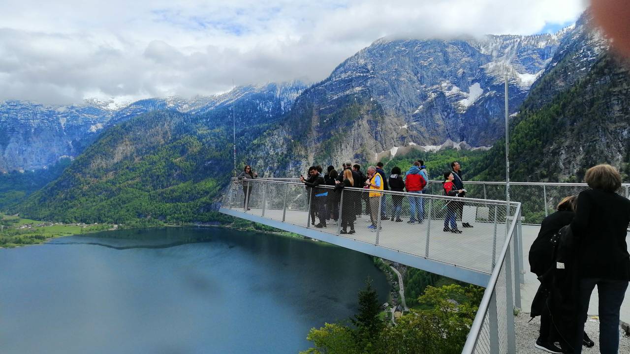 Touristen und Touristinnen stehen am 16. Mai 2023 auf einer Aussichtsplattform über dem Hallstätter See in Österreich.