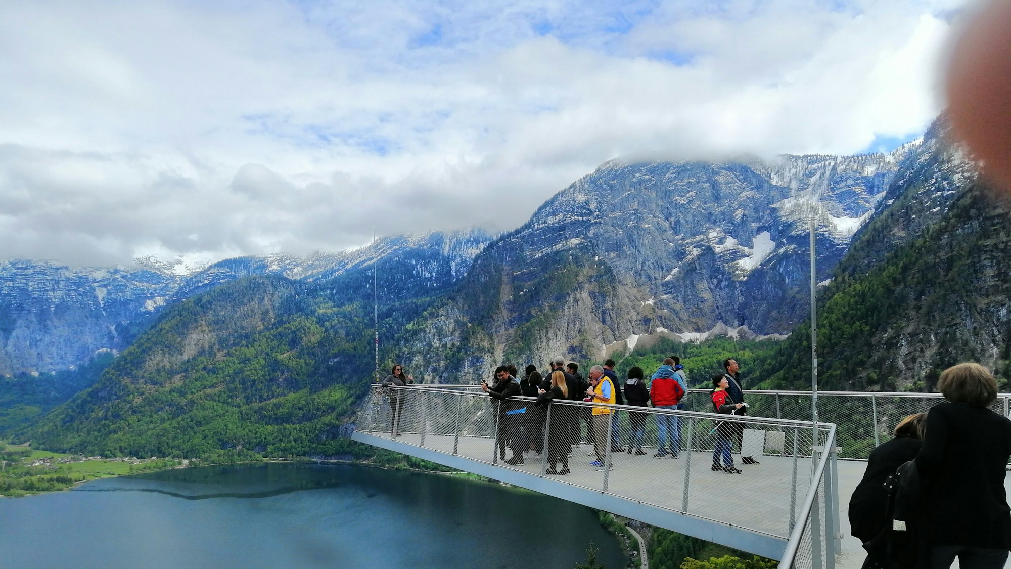 Touristen und Touristinnen stehen am 16. Mai 2023 auf einer Aussichtsplattform über dem Hallstätter See in Österreich.