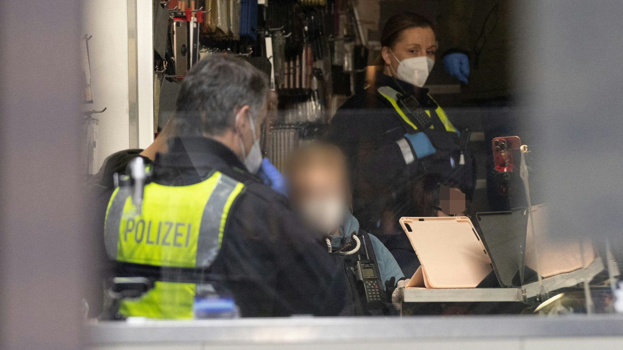 Zwei Einsatzkräfte der Polizei stehen in einem Laden.