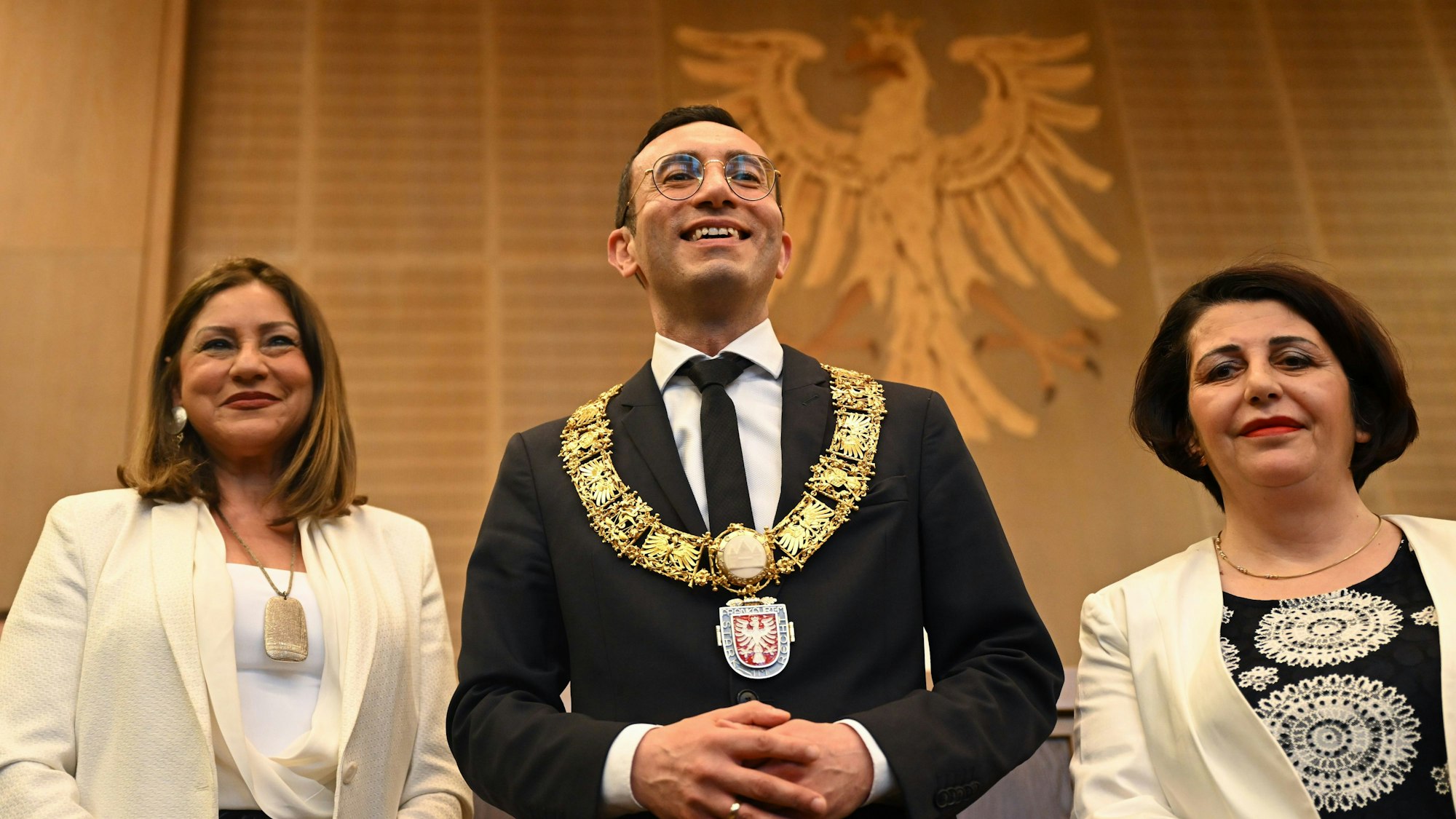Der neue Frankfurter Oberbürgermeister Mike Josef (SPD) steht bei seiner Amtseinführung während der Stadtverordnetenversammlung im Rathaus Römer mit der goldenen Amtskette zwischen Stadtverordnetenvorsteherin Hilime Arslaner (r) und Bürgermeisterin Nargess Eskandari-Grünberg (beide Bündnis 90/Die Grünen).