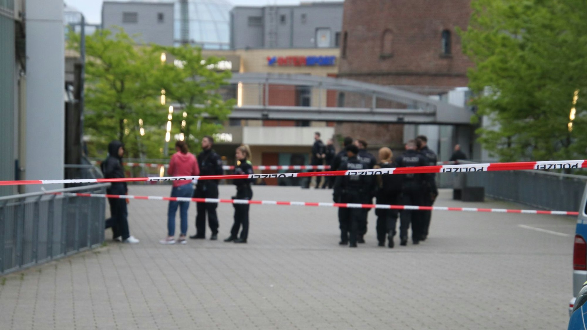 Mehrere Einsatzkräfte stehen in einem Bereich, der mit Flatterband abgesperrt ist.