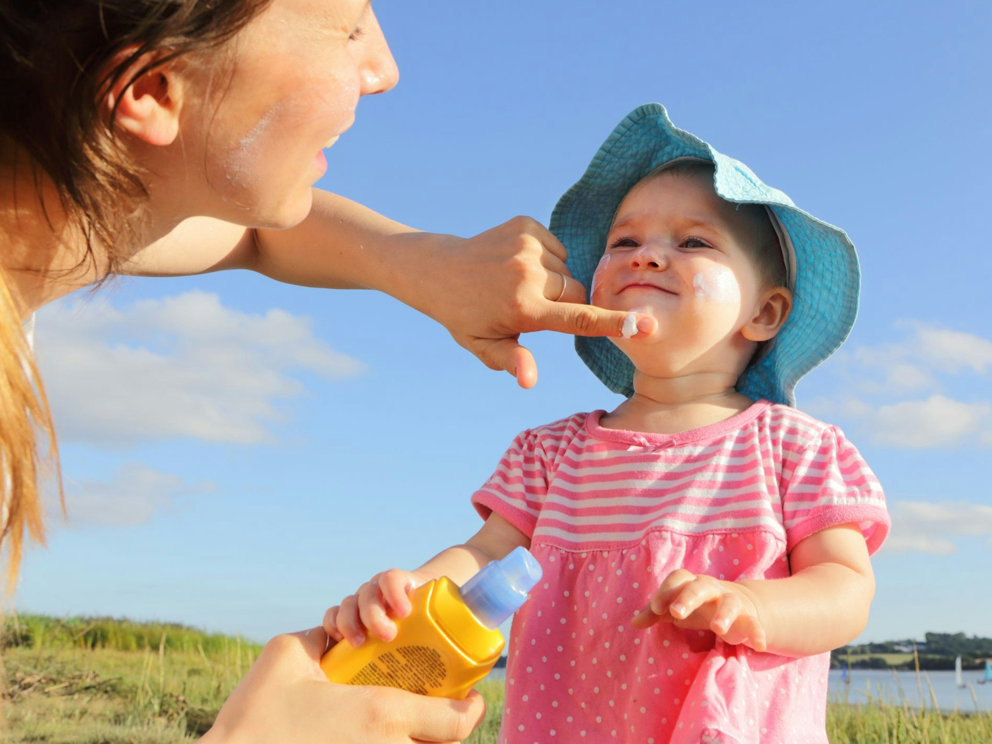 Ein Kind wird von seiner Mutter mit Sonnencreme eingeschmiert.