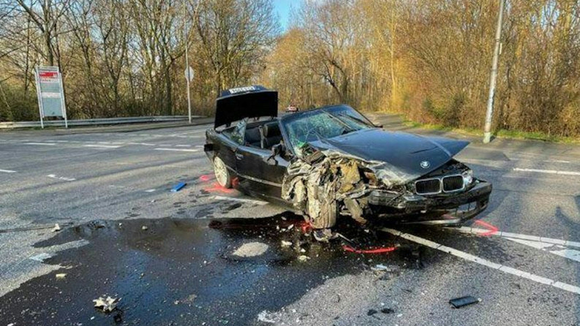 Ein zerstörter BMW liegt alleine auf einer Straße in Köln.