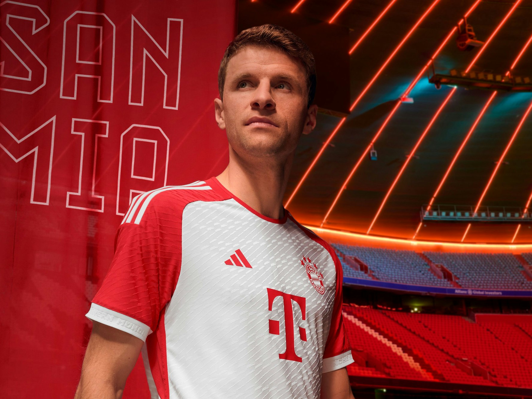 Thomas Müller posiert im neuen Heimtrikot. Die Ärmel des Trikots sind rot, die Grundfarbe weiß.